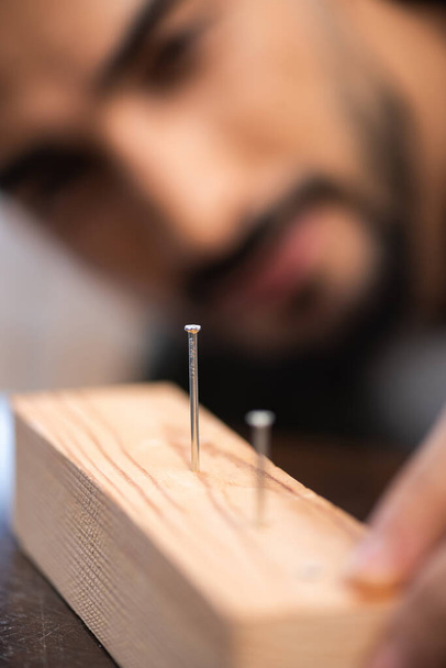 Blurred repairman looking at nails in wooden board  - Foto, imagen
