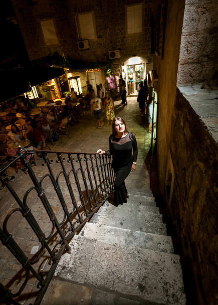 Nachtaufnahme einer Frau in Kleid, die die Treppe auf der Straße hinaufgeht - Foto, Bild