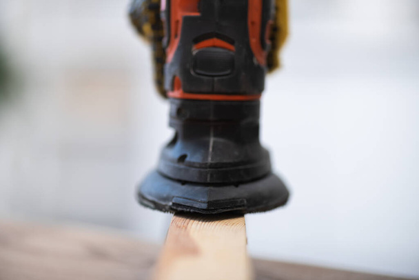 Close up view of blurred electric sander on wooden board at home  - Photo, image