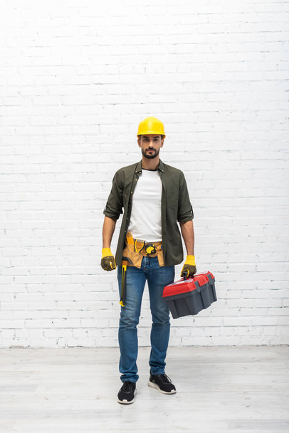 Arabian man in hardhat holding toolbox at home  - Photo, image
