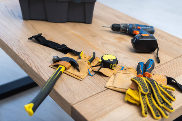 Tools in belt near blurred box and electric screwdriver on table  - Zdjęcie, obraz