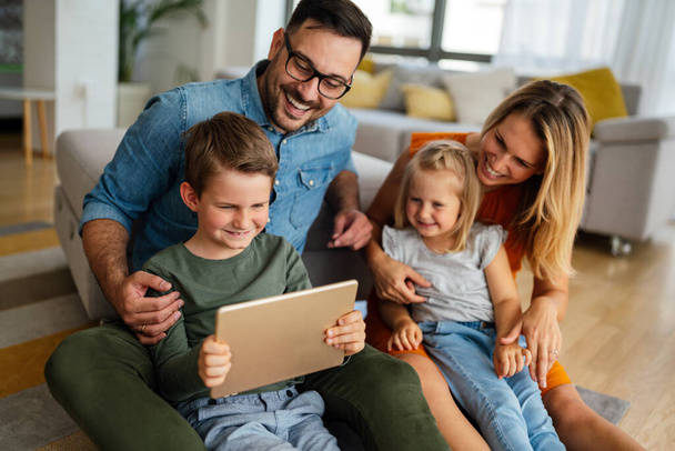 Happy young family having fun time at home. Parents with children using digital device. Education parenting happiness concept. - Foto, Bild