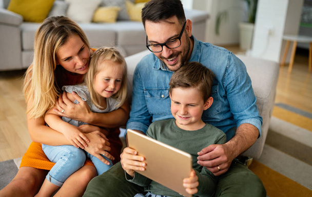 Happy young family having fun time at home. Parents with children using digital device. Education parenting happiness concept. - Foto, imagen