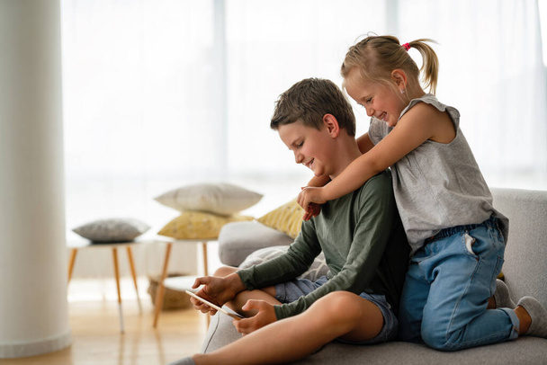 Little girl and boy watching video or playing games on their digital device tablet, smartphone. Children digital addiction concept. - Photo, Image