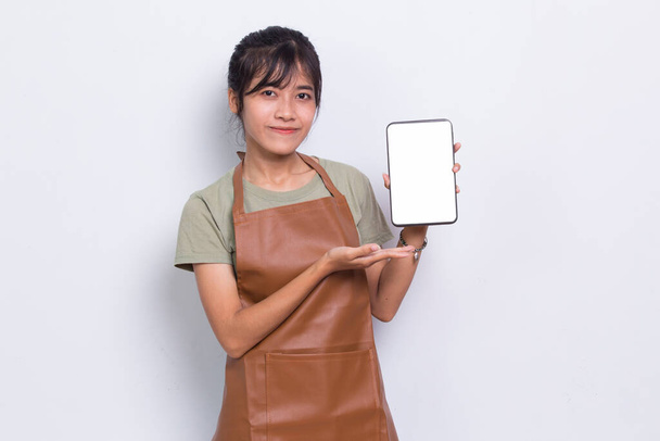 Piękna azjatycka kelnerka Barista demonstrująca telefon komórkowy na białym tle - Zdjęcie, obraz
