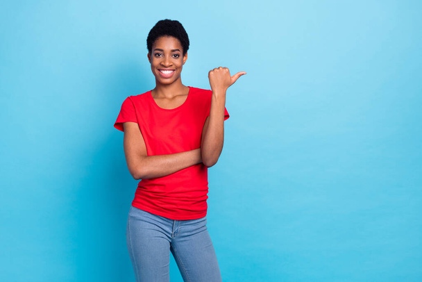 Photo of cheerful charming short hair person dressed red t-shirt pointing thumb empty space isolated blue color background. - Foto, Imagen