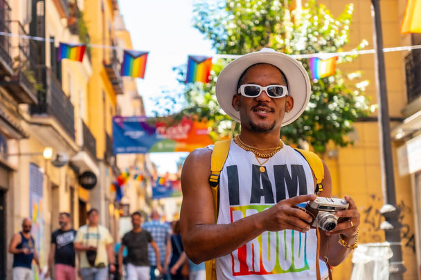 A gay black man at the pride party with a camera, LGBT flag - Foto, imagen