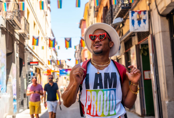 A tourist man of gay black ethnicity enjoying and smiling at the pride party, LGBT flag - Photo, Image