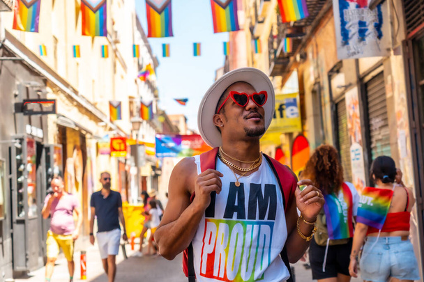 A gay black ethnicity man enjoying and smiling at the pride party, LGBT flag - Foto, imagen