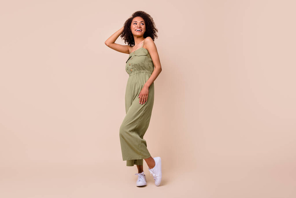 Full length photo of lovely young girl touch wavy hair posing shopping promo wear stylish khaki outfit isolated on beige color background. - Fotó, kép