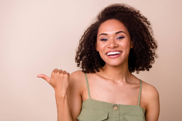Photo of optimistic gorgeous cheerful girl with wavy hairstyle wear khaki top showing empty space isolated on beige color background. - Zdjęcie, obraz