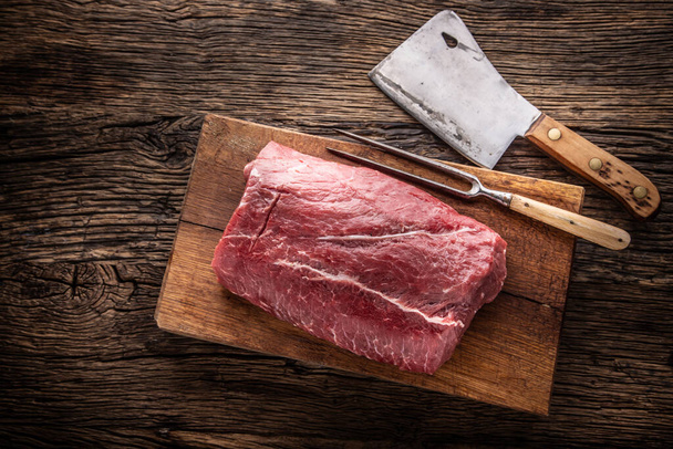Raw rib eye steak whole on a wooden board with fork and chopping knife - Top of view. - Photo, Image