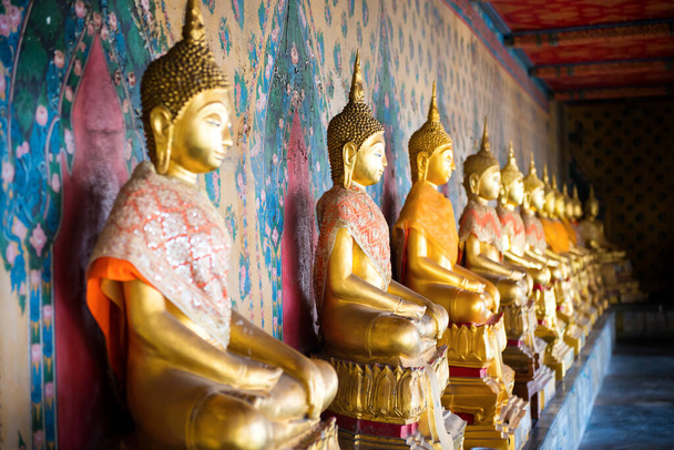 Vue en perspective des statues en or rangées de bouddhas assis dans le temple Wat Arun. Bangkok, Thaïlande
 - Photo, image