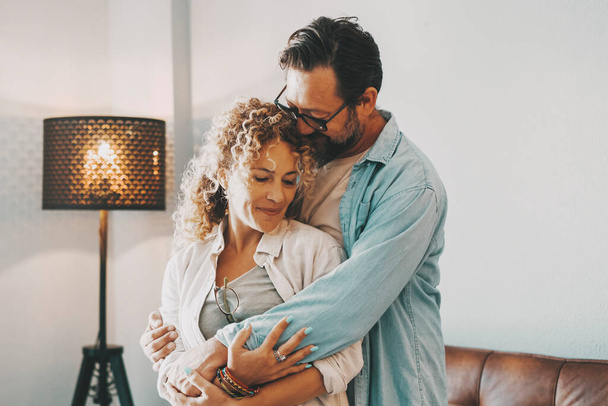 Romantic love and relationship with young couple hugging at home. Intimacy and romance with man and woman family. New home happiness concept emotion. People enjoying time together embracing tenderness - 写真・画像