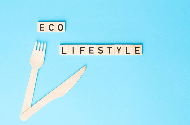ECO LIFESTYLE sign made by wooden cubes with wooden cutlery on the side on the blue backhround. Zero waste, ecological concept. - 写真・画像