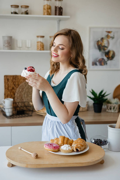 Housewife holding a cake in her hands while standing in the kitchen. High quality photo - Photo, image