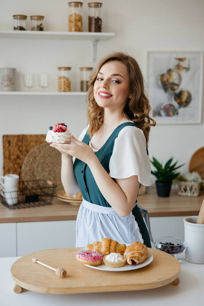 Housewife holding a cake in her hands while standing in the kitchen. High quality photo - Fotó, kép