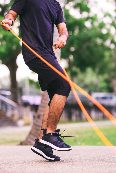 Fitness concept. Healthy lifestyle. Man in black jumping with skipping rope in the park. - Φωτογραφία, εικόνα