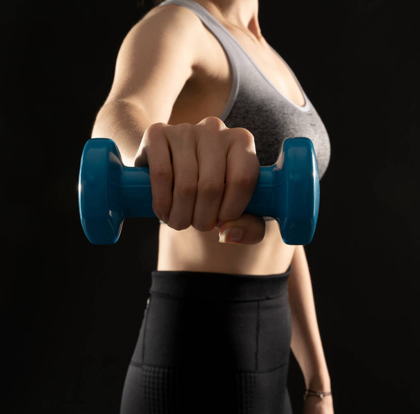 Close up photo of healthy woman working out with dumbbells on the black background - Foto, Imagen