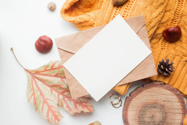 fall mockup card with autumn leaves invitation card with environment and details Mockup with postcard and sweater with wood elemets on white background. - Foto, imagen