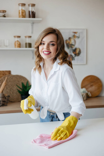 Housewife in yellow gloves wipes the kitchen table. High quality photo - Foto, Imagem