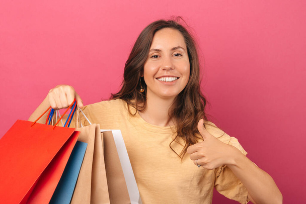 A picture of a young woman holding some shopping bags and her being happy and thankful about it  - Фото, изображение