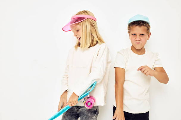 Porträt von zwei jungen lächelnden Kindern in Mützen mit hellem Skateboard-Hintergrund. Hochwertiges Foto - Foto, Bild