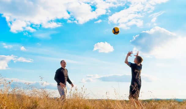 People play ball in nature against a blue sky with white clouds - Fotó, kép