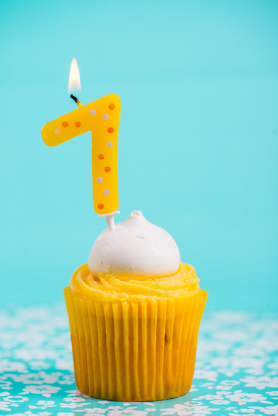 eerste cup-cake van de kindverjaardag met nummer een kaars op blauwe pagina - Foto, afbeelding