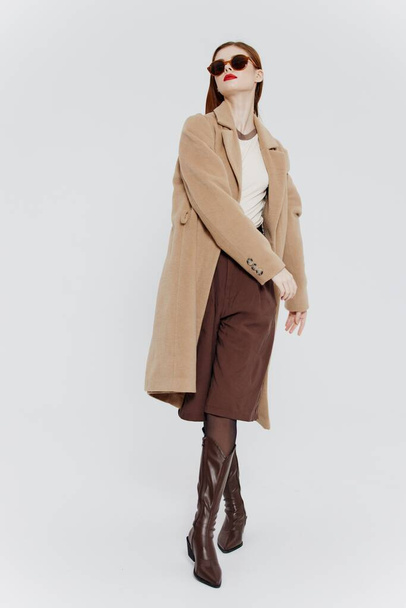 Élégante dame rousse en manteau beige posant sur un fond blanc en studio. Photo de haute qualité - Photo, image