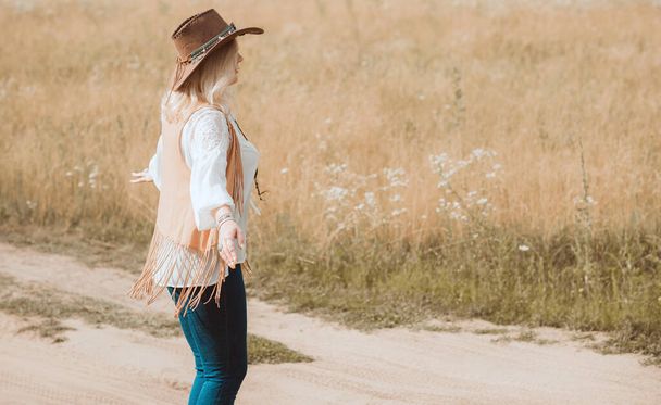 Woman Plus size in American country style black boho jacket, with a fringe, shirt and cowboy hat at nature - Foto, Imagem