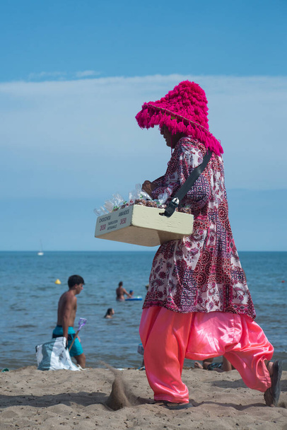 Valras - France - 28 July 2022 - Portrait of colorful beach seller walking on the sand - Fotografie, Obrázek