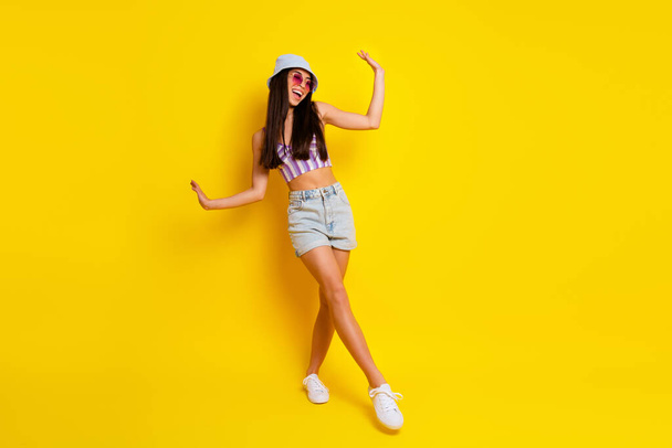 Full length picture of cheerful young lady on summer vacation dancing near pool resort isolated on yellow color background. - 写真・画像