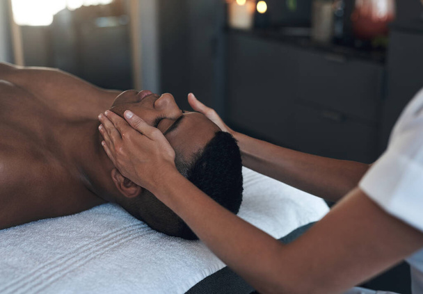 Well take care of your whole body. a young man getting a face massage at a spa - Fotó, kép