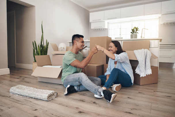This is the first of many other things well achieve together. a couple sharing a fist bump while moving into their new home - Foto, imagen