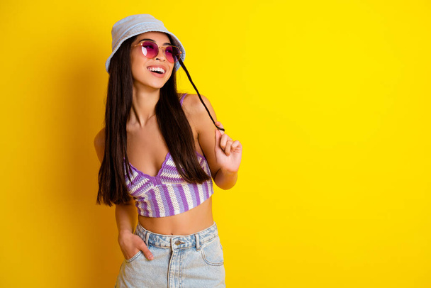 Photo of cute dreamy female in swimwear top enjoying her summer weekend near sea isolated on yellow color background. - Foto, imagen