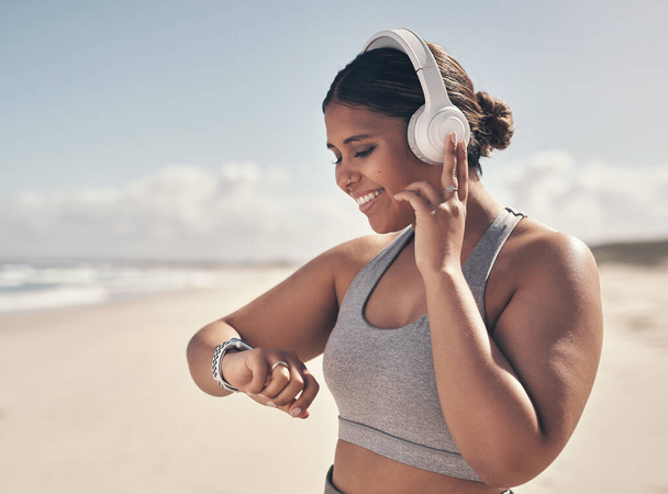 A little progress is better than no progress at all. a young woman wearing a smartwatch and headphones while out for a run - Foto, afbeelding