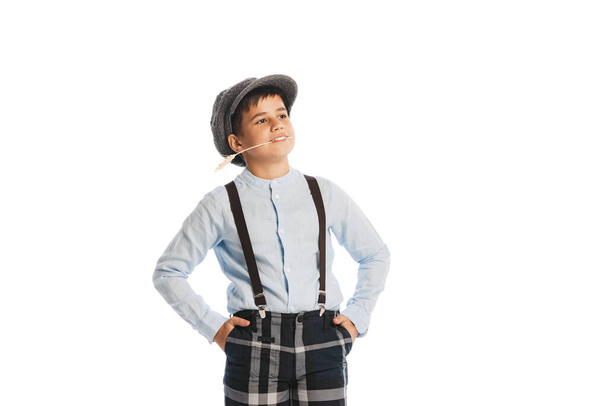 Portrait of stylish kid, boy in shirt, cap, suspenders and plaid pants smiling, posing isolated over white studio background. Concept of childhood, friendship, fun, lifestyle, fashion. Retro style - Photo, Image