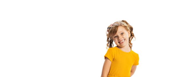 Portrait of little emotive kid, girl in yellow dress posing, making faces isolated over white studio background. Concept of childhood, friendship, fun, lifestyle, fashion. Retro style - Photo, Image