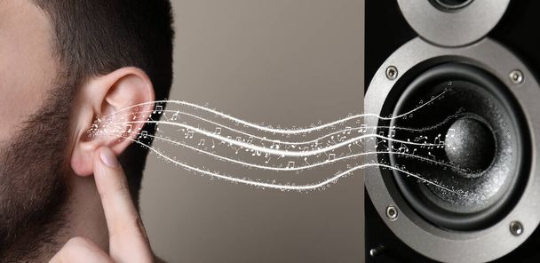 Modern audio speaker and man listening to music on light grey background, closeup view of ear. Banner design - Foto, Bild