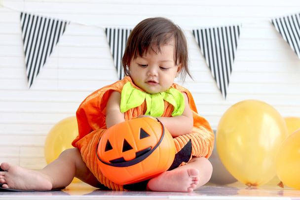Adorable baby girl kid dressing up in orange fancy Halloween pumpkin costume, cheerful little cute child go to party, playing trick or treat, Happy Halloween celebration. - Zdjęcie, obraz