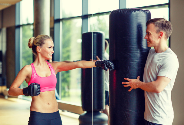 smiling woman with personal trainer boxing in gym - Fotografie, Obrázek