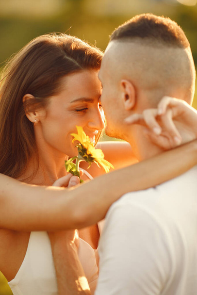 Young loving couple is kissing in a sunflower field. Portrait of couple posing in summer in field. - Foto, Bild