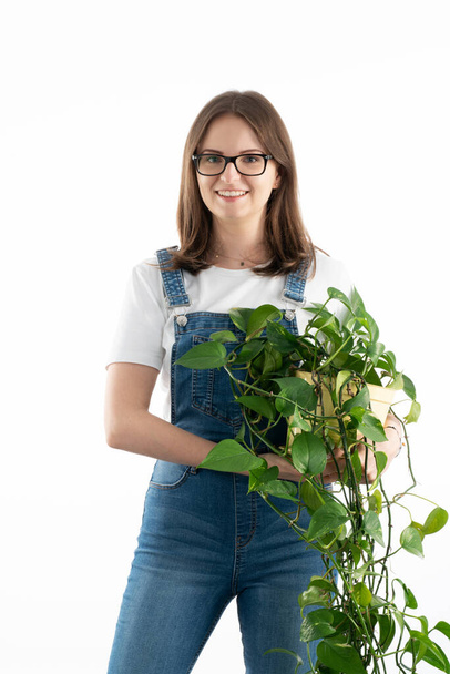 Young and happy caucasian woman with beautiful green potted flower in her hands. - Фото, зображення