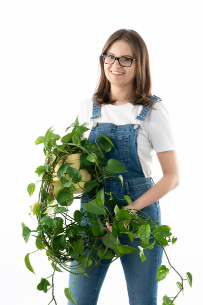 Young and happy caucasian woman with beautiful green potted flower in her hands. - Фото, изображение