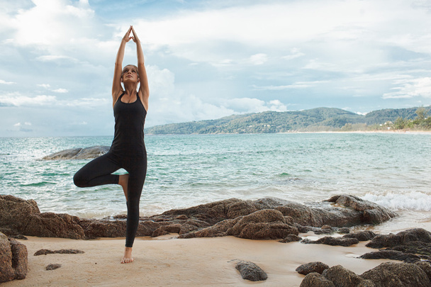 women doing yoga with the ocean behind - Foto, imagen