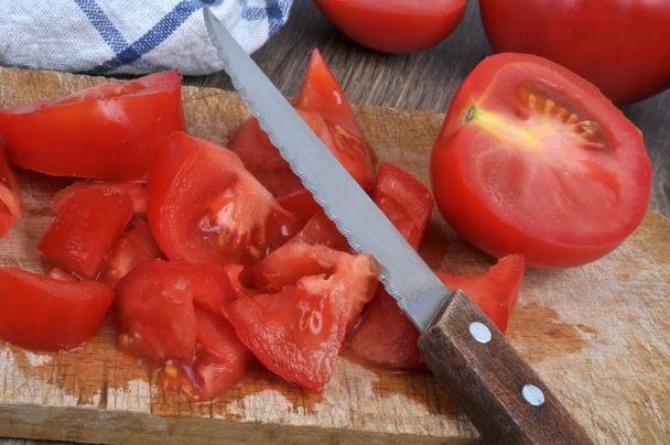 Tomatoes cut into small pieces with a knife on a cutting board close-up - Foto, afbeelding