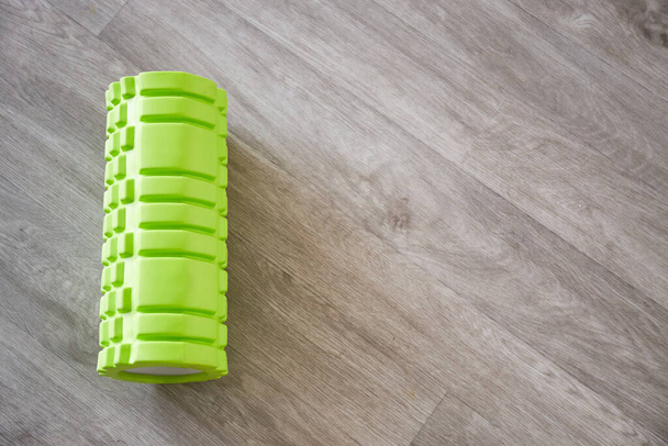Green foam sport roller for self-massage. Home fitness accessories. Flexibility and mobility, body strength - Φωτογραφία, εικόνα