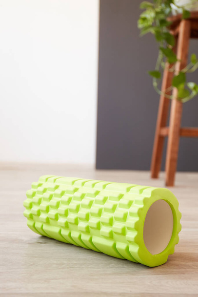 Green foam sport roller for self-massage. Home fitness accessories. Flexibility and mobility, body strength - Foto, afbeelding