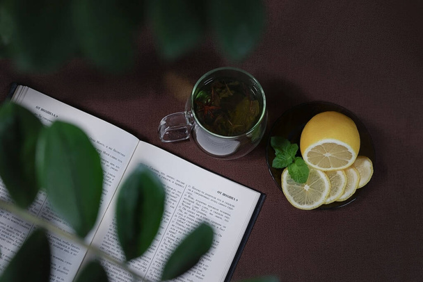 an open bible lies on the table next to a cup of tea - Fotoğraf, Görsel